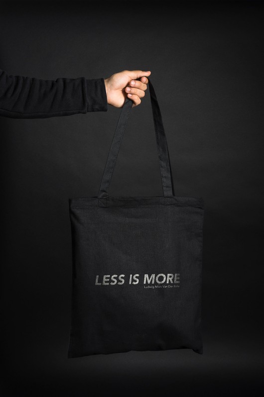 a-hand-is-holding-a-black-tote-bag-less-is-more