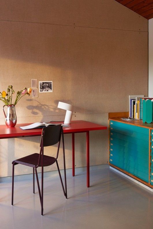 lampe-slant-blanche-dans-un-bureau-avec-murs-beiges-chaise-vase-fleuri-et-etageres